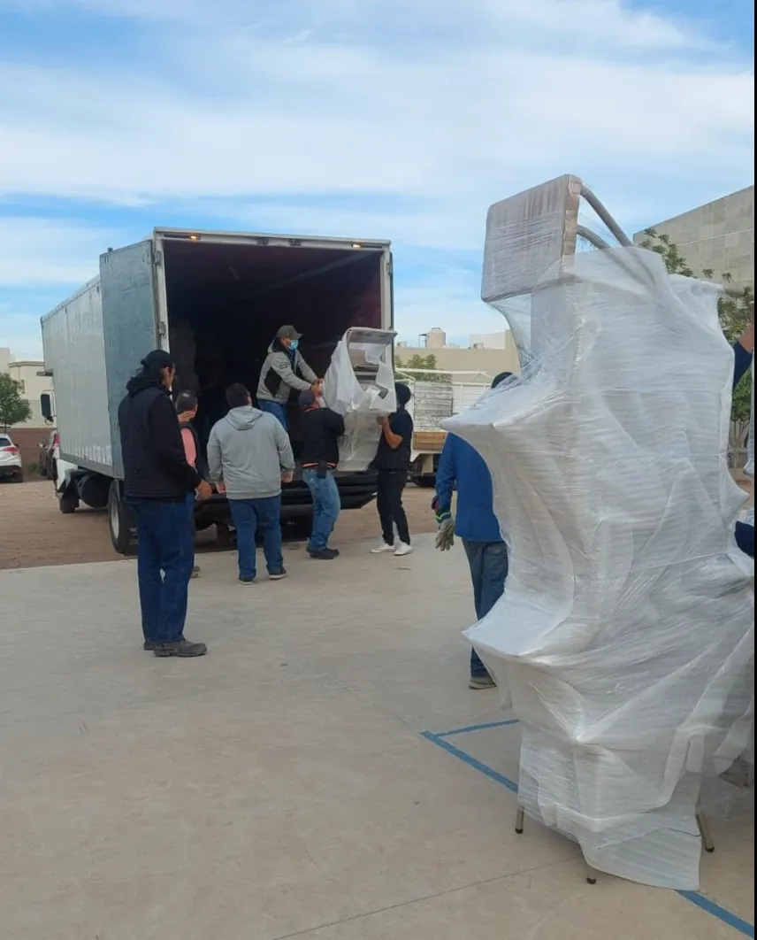 Cuadrilla de GDL Transportes descarga mobiliario emplayado de una caja seca.